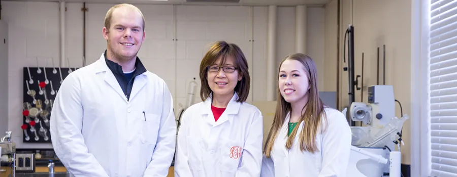 chemistry professor standing with students inside a lab