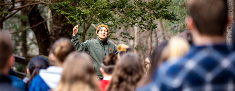 woman directs crowd in forest