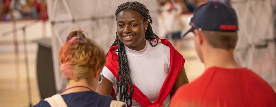 Young woman greeting students at a campus event
