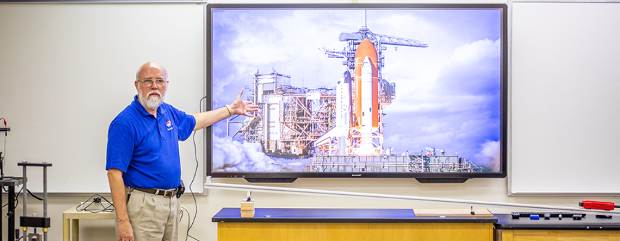 professor in front of screen with rocketship