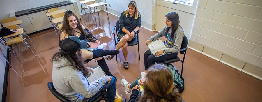 Professor sitting in a circle with students in the classroom.
