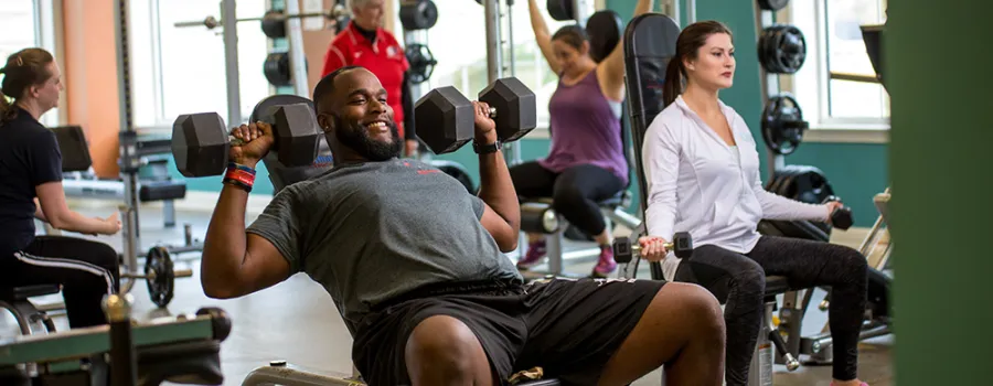 Adults exercising in weight room