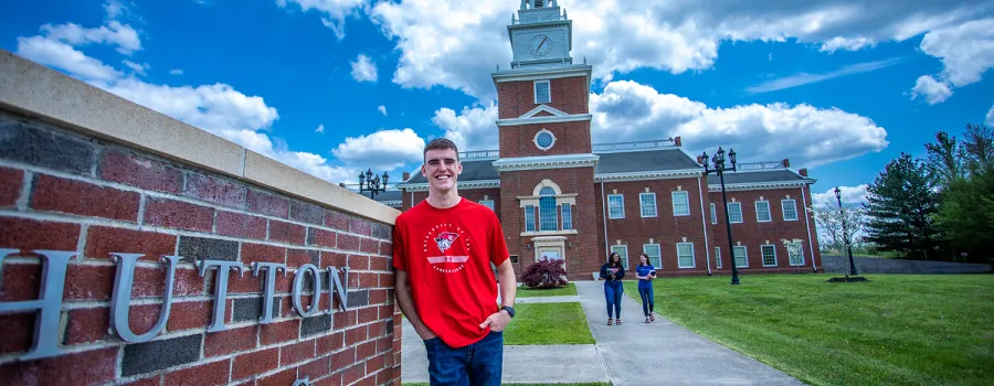A business student stands in front of the business school 