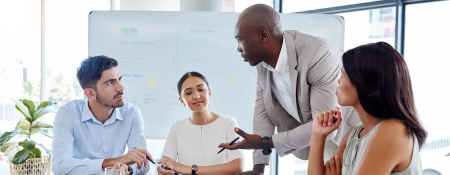 A group of business professionals discuss a project around a table.