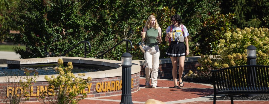Two female students are walking in the quad while talking. 