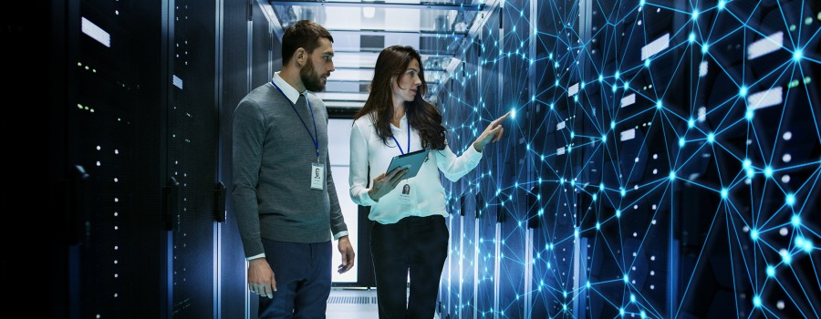 A man and a woman with security badges look at a digital server mapping machine learning patterns.