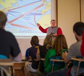 Dr. Coleman pointing to a projector with students facing him in the foreground.