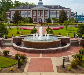 A water fountain in the middle of the college campus. 
