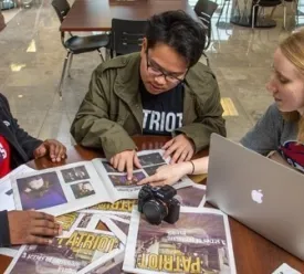 Three people sitting while looking at Newspapers