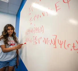 Student explains math equation on whiteboard