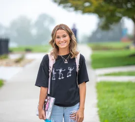 Young woman wearing backpack standing outdoors.