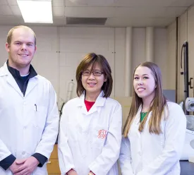 chemistry professor standing with students inside a lab