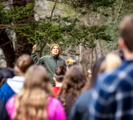 woman directs crowd in forest