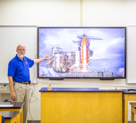 professor in front of screen with rocketship