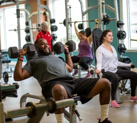 Adults exercising in weight room