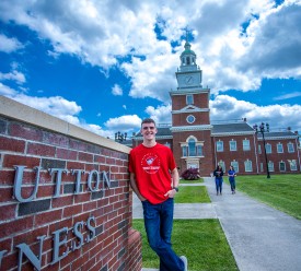 A business student stands in front of the business school 