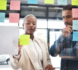 Two professionals work discuss marketing notes.