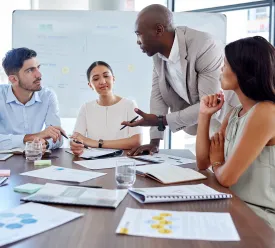 A group of business professionals discuss a project around a table.