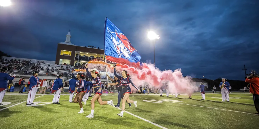 Cheerleaders lead the football team out on to the field