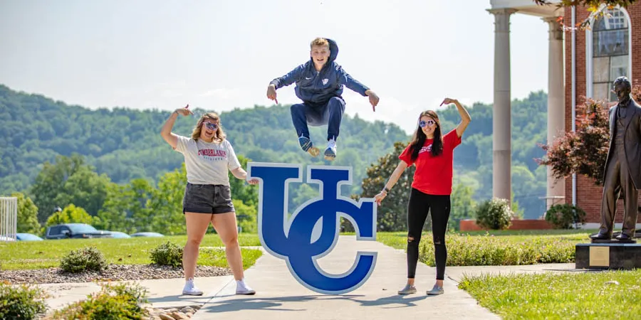 Student leaping over UC sign