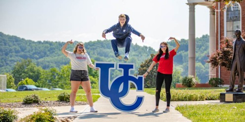 Student leaping over UC sign