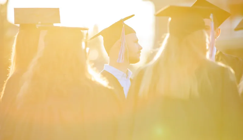 Students wearing cap and gown at sunset