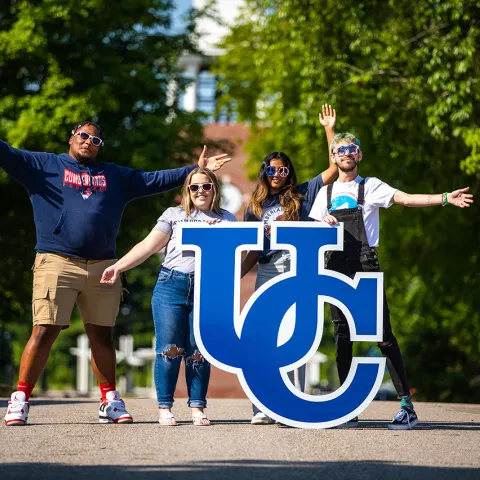 University of the Cumberlands student pose on campus with a UC sign. 