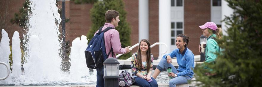 University of the Cumberlands students sitting at a fountain on campus talking and laughing.