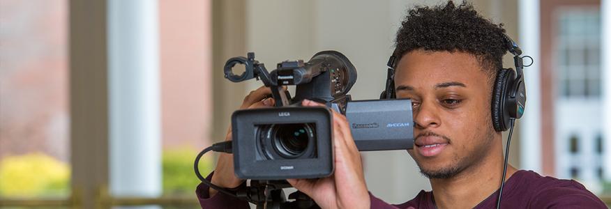 A communications major student working with a video camera.