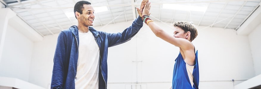 A sports coach, with an associate's in coaching, degree giving a high-five to an athlete.