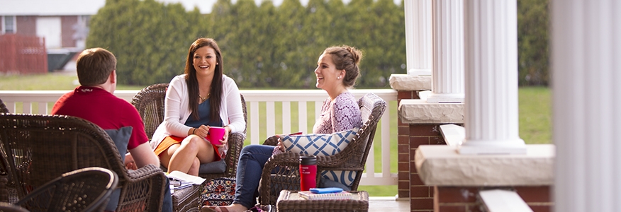 Three bachelor in psychology degree students studying together on a porch on the University of Cumberlands campus.