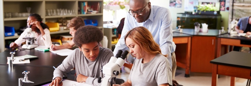 Teacher with two students and a microscope