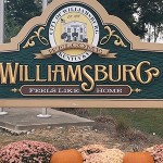 Two students standing by a sign 