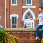Two students sitting on a wall outside