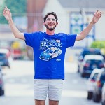 Student posing for a picture with both arms up