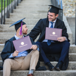 Two graduates display their diplomas