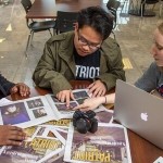 Three people sitting while looking at Newspapers