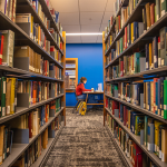 A student studying in the new library with books in the foreground. 