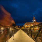 A student walks across the viaduct at night. 