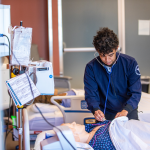 A nursing student works through an exam on a simulated patient. 