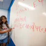 Student explains math equation on whiteboard