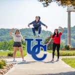 Student leaping over UC sign