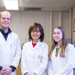 chemistry professor standing with students inside a lab