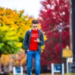A student looking at their phone while walking