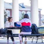 Two students seated at a table ouside