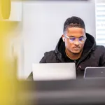 A student using a laptop indoors. 