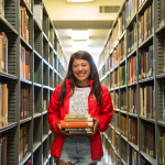 girl standing holding books in library