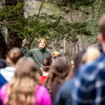 woman directs crowd in forest