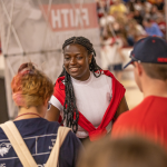 Young woman greeting students at a campus event