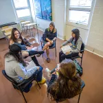 Professor sitting in a circle with students in the classroom.